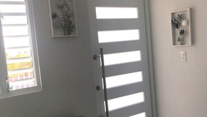 Ein Zimmer mit einem grünen Sofa, einer Tür mit horizontalen Rollläden und zwei gerahmten Bildern an der Wand.