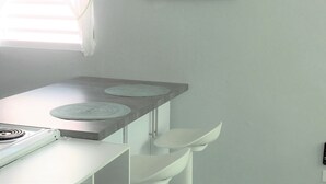 Eine Küche mit einer weißen Arbeitsplatte, zwei runden Teppichen, einem weißen Stuhl und einem spiralförmigen Kunstwerk an der Wand.