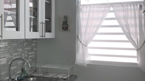 Eine Küche mit doppeltem Spülbecken, weißen Schränken und einem Fenster mit transparenten Vorhängen.