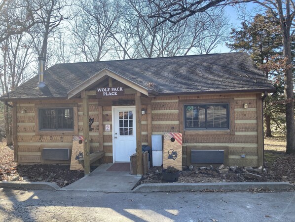 A small wooden building labeled "Wolf Pack Place" with a front door, windows, and a no-smoking sign.