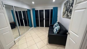 Una habitación con sofá negro, cortinas color turquesa y un espejo grande.