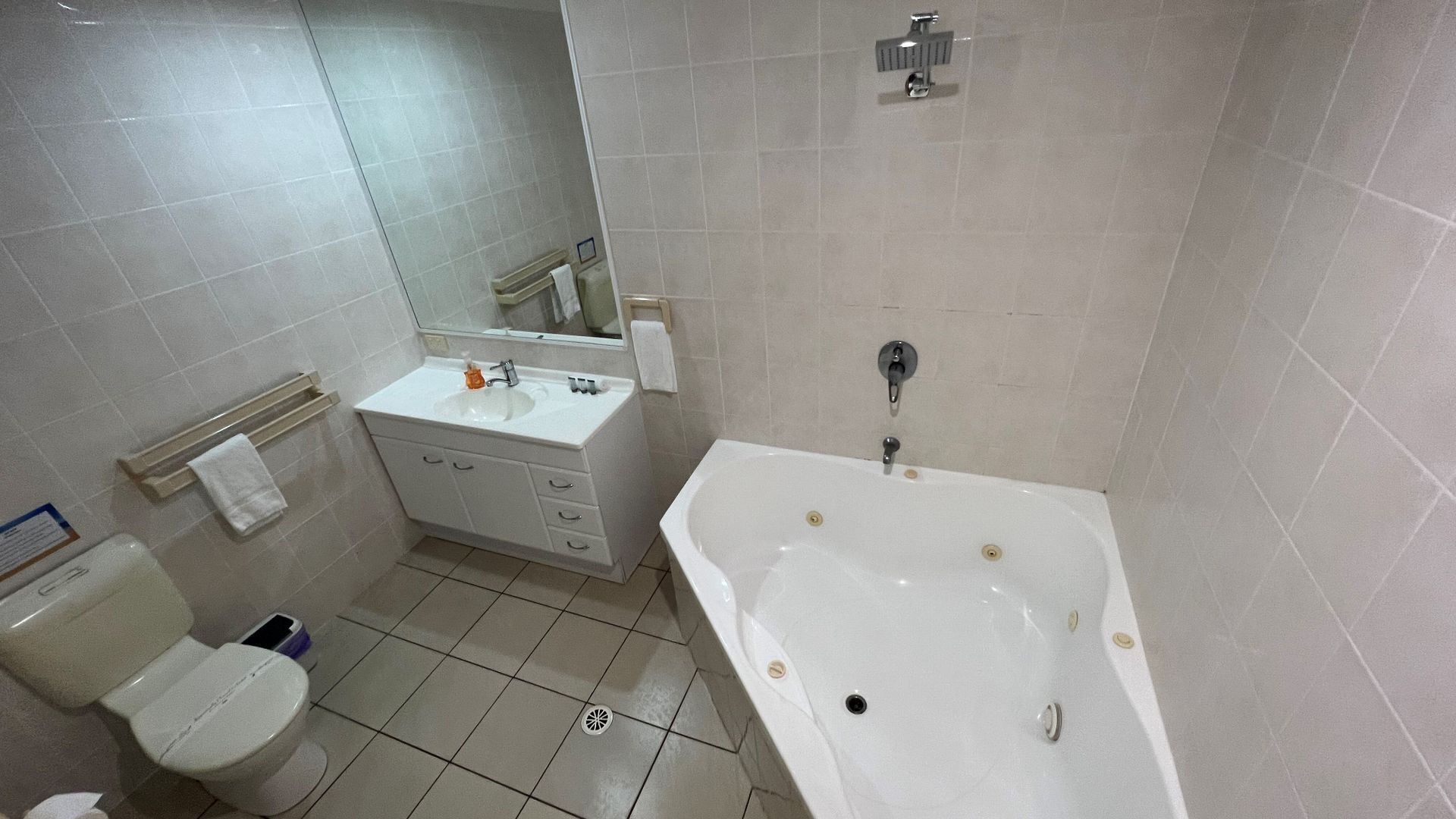 A bathroom with a white sink, mirror, and bathtub. There is a toilet and a towel rack.