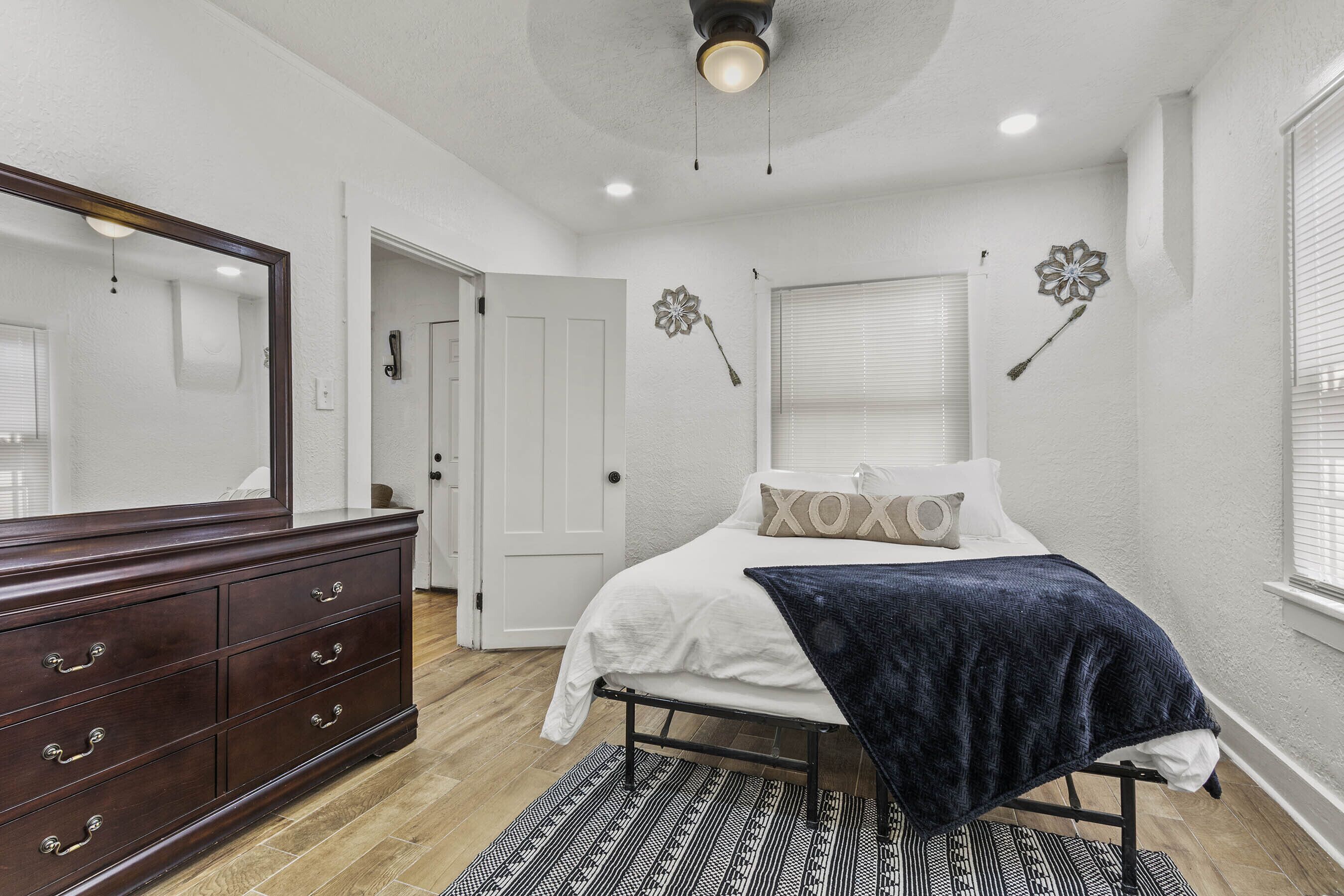 A bedroom with a bed, dresser, and a ceiling fan.