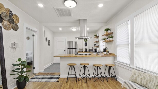 A modern kitchen with a central island, bar stools, and a dining area with a bench.