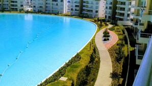 Un complex d'apartaments modern amb una gran piscina, un camí corbat i nombrosos balcons.