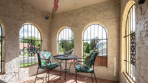 A sunlit patio with three arched windows, a round table, and two chairs with colorful upholstery. - Spacious (2/1, 1100 sqf) - 5 -15 minutes to Airport, Downtown, SeaWorld, etc. (San Antonio)