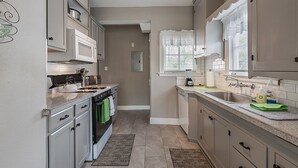 A kitchen with white cabinets, a microwave, a stove, and a sink. - Spacious (2/1, 1100 sqf) - 5 -15 minutes to Airport, Downtown, SeaWorld, etc. (San Antonio)