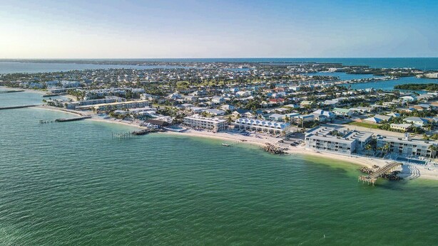 An aerial view of a coastal resort area with buildings, a beach, and a pier. - Oceanview Condo 2bed/2bath beachfront condo in Key Colony Beach (Key Colony Beach)