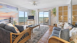 A spacious living room with a large TV, comfortable seating, and a balcony with a view of the ocean. - Oceanview Condo 2bed/2bath beachfront condo in Key Colony Beach (Key Colony Beach)