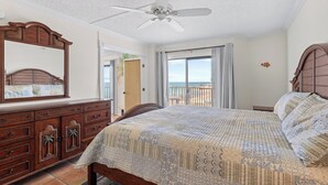 A bedroom with a large bed, a ceiling fan, a dresser, and a view of the beach through a balcony. - Oceanview Condo 2bed/2bath beachfront condo in Key Colony Beach (Key Colony Beach)