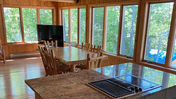 A spacious kitchen with a large island, wooden cabinets, and a dining area with a table and chairs.