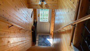 A wooden interior with a staircase leading to a door with a window.