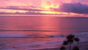 A sunset over the ocean with a beach and palm trees in the foreground. - Ocean-Front Beach Bungalow with Two Bedrooms and a shared Ocean-Front deck (San Clemente)