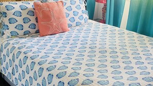 A bed with a blue and white fish pattern bedspread, a wooden headboard, and a single pink pillow. - Ocean-Front Beach Bungalow with Two Bedrooms and a shared Ocean-Front deck (San Clemente)