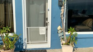 A building with a blue exterior, a white door with a 'C' sign, and potted plants in front. - Ocean-Front Beach Bungalow with Two Bedrooms and a shared Ocean-Front deck (San Clemente)