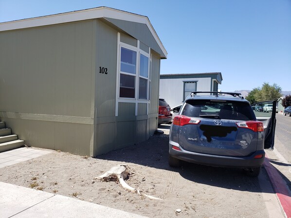 A building with the number 102 on its side, a parked SUV, and a clear sky. - Short, long, pets, kids.... Take a peek stay a night or two! (Fernley)