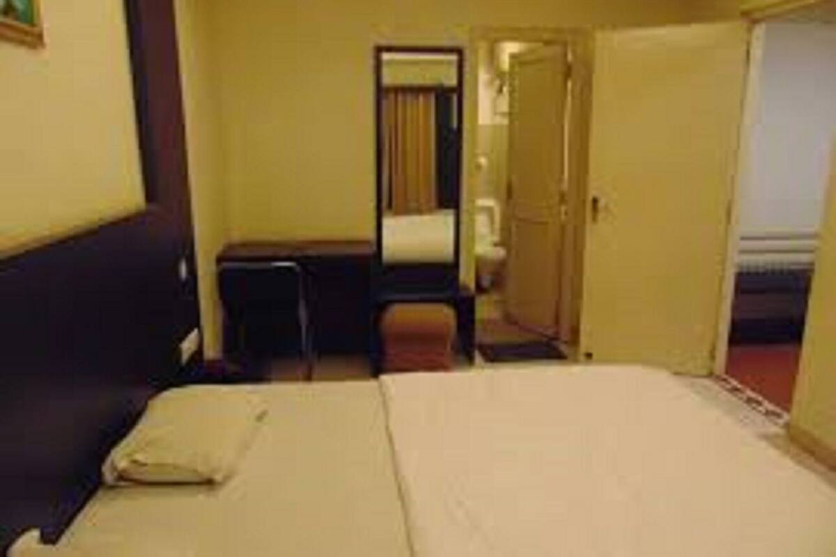 A hotel room with a bed, a desk, and a mirror.