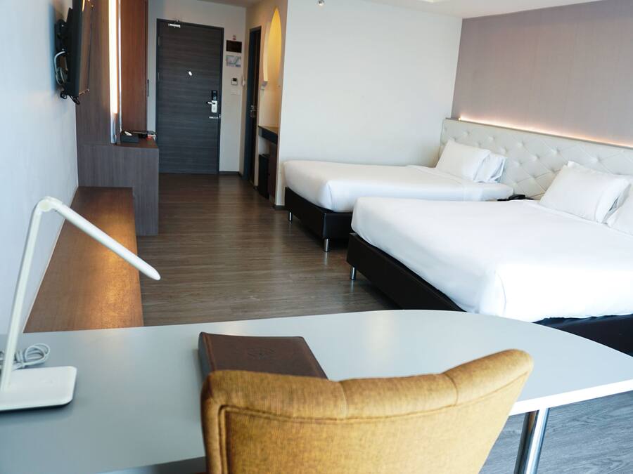 Quarto de hotel com cama, mesas de cabeceira, escrivaninha e cadeira.