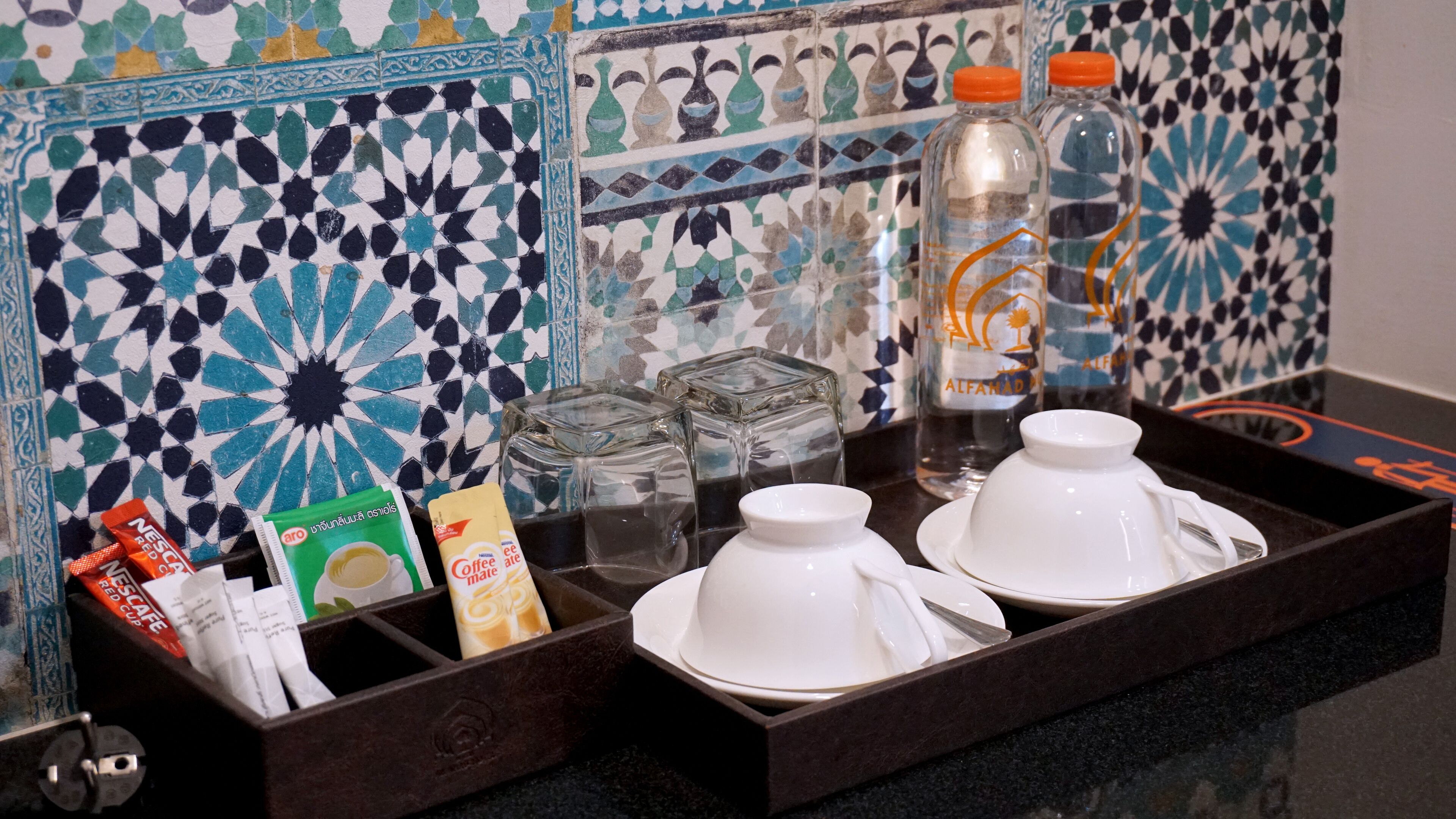 Una bandeja con tazas de café, una botella de agua y una caja de leche para café.