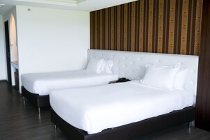 Habitación de hotel con dos camas, cabecero de madera y diseño de papel tapiz a rayas.
