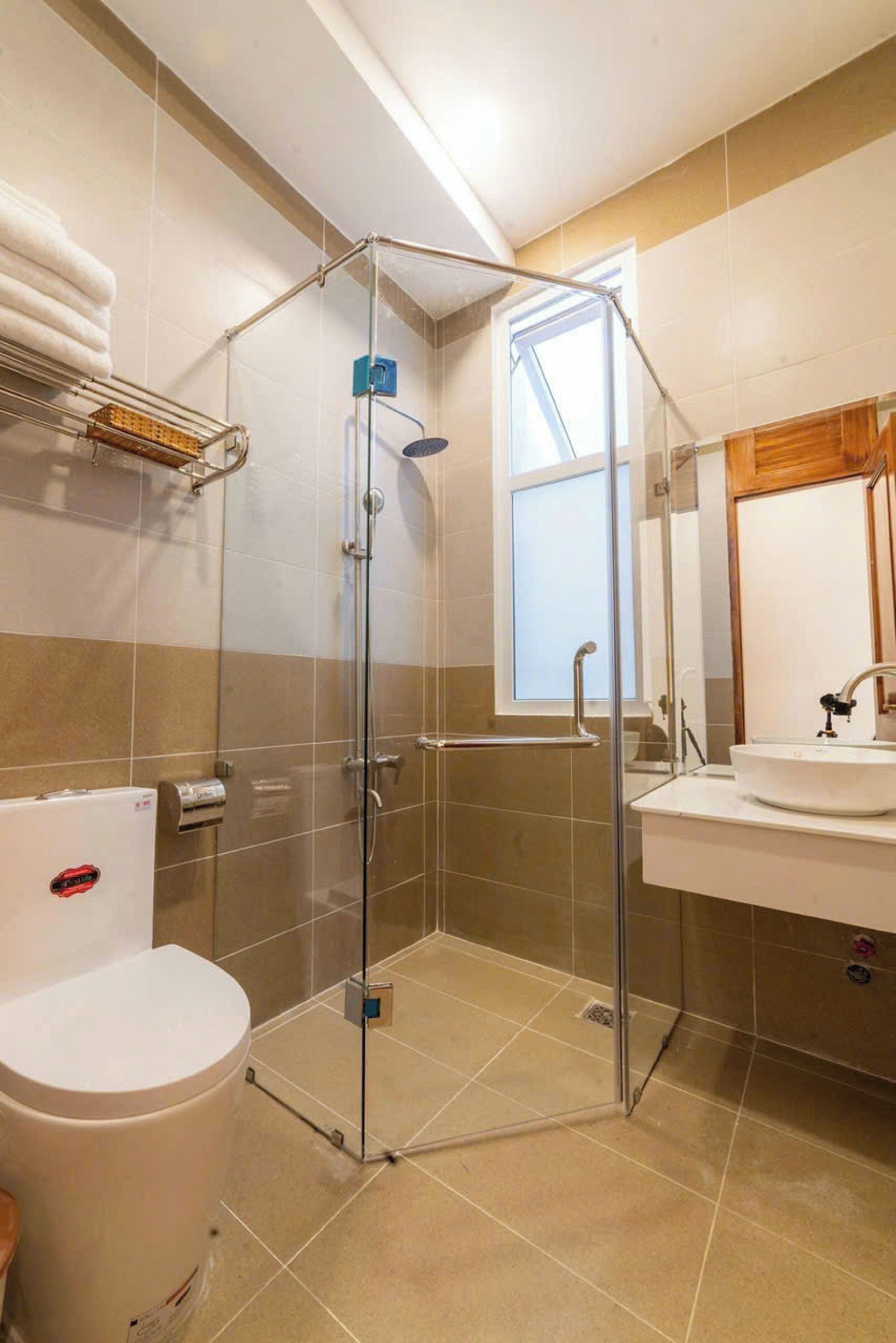 A bathroom with a glass-enclosed shower, a toilet, and a sink with a mirror.