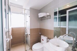 A modern bathroom with a glass shower enclosure, a toilet, a sink, and a mirror. - Cherry House Dalat (Lam Vien - Da Lat)