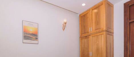 A hotel room with a bed, a nightstand, a wooden wardrobe, and a wall-mounted light fixture.