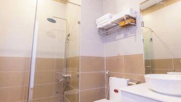 A modern bathroom with a glass-enclosed shower, a toilet, and a sink with a towel rack above.