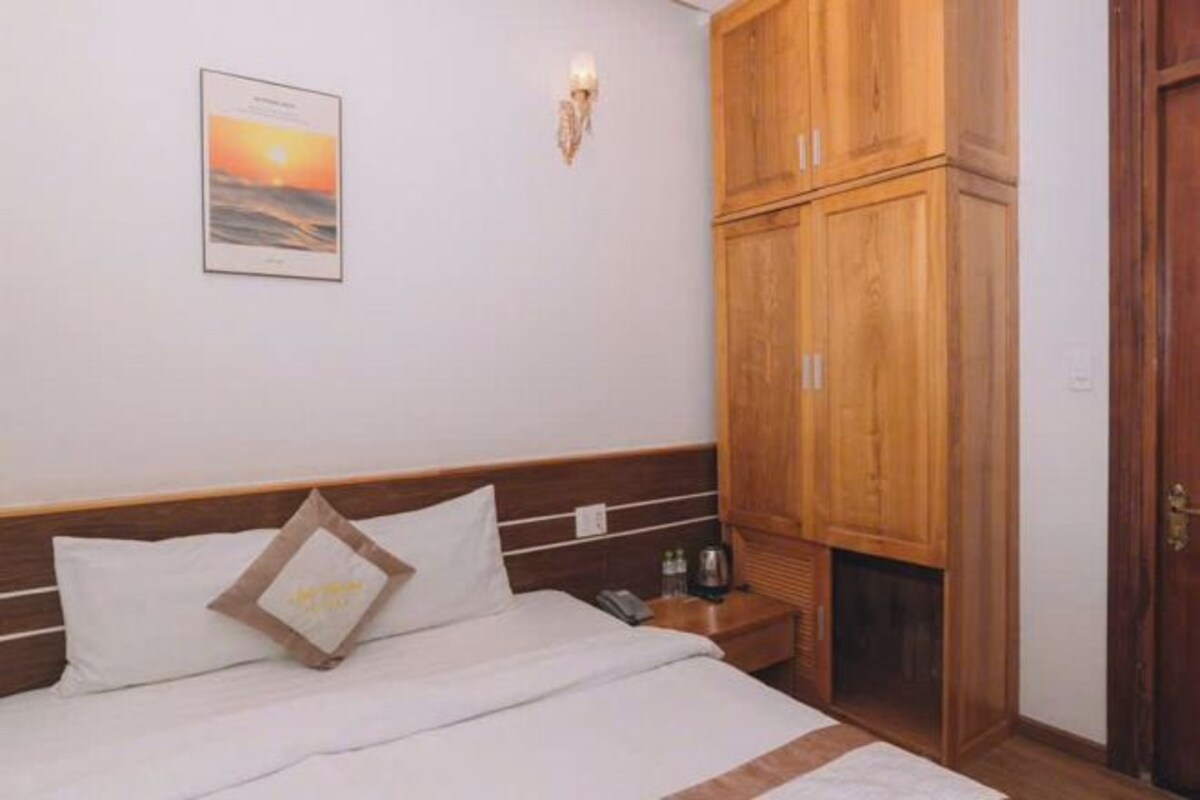 Une chambre à coucher avec un lit, une armoire en bois et un luminaire fixé au mur.
