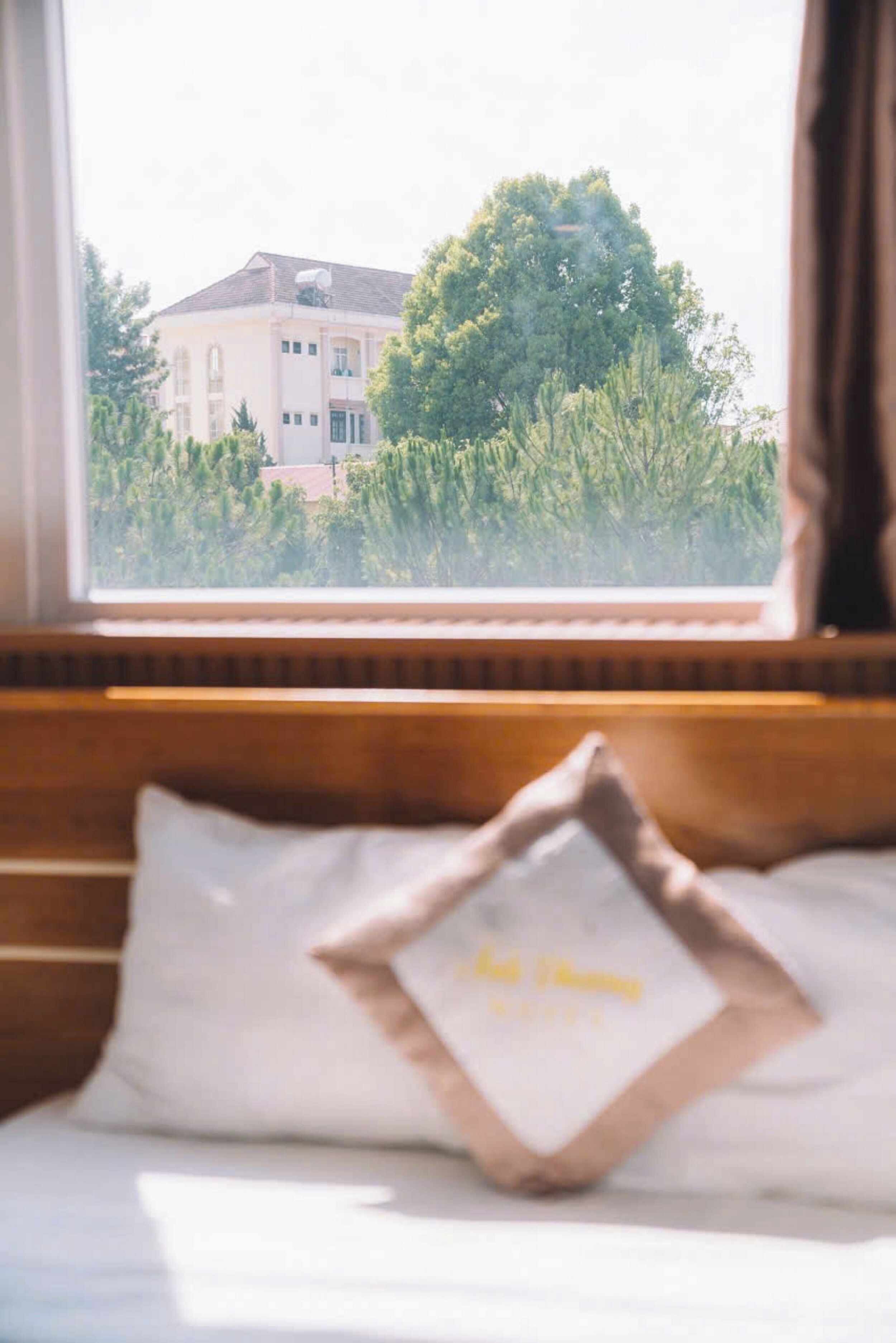 Un dormitorio con vista a un edificio y árboles desde la ventana.