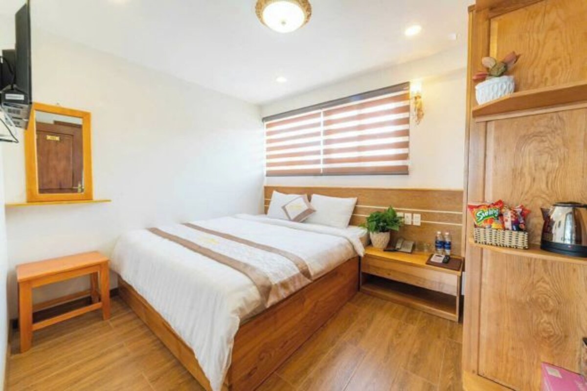 Une chambre d’hôtel avec un lit en bois, une table de chevet et une armoire.