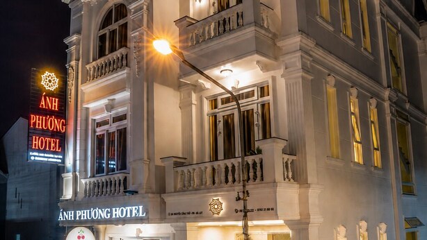 Ein mehrstöckiges Hotel mit klassischer Architektur, das mit Balkonen und einem gut beleuchteten Eingang besticht.