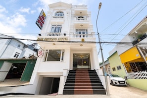 Entrada de hotel con una escalera que conduce a la puerta, un letrero encima y un farol en primer plano.