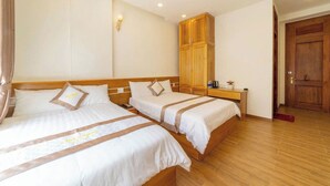 Ein Hotelzimmer mit zwei Betten, einem Holzschrank, einem Nachttisch mit Lampe und einer Tür.