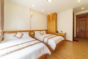 A hotel room with two beds, a wooden wardrobe, a nightstand with a lamp, and a door. - Cherry House Dalat (Lam Vien - Da Lat)