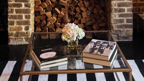 A brick fireplace with a sign above it, a glass coffee table with books and a vase, and a striped rug on the floor. - Luxury Townhouse Chic Flat in the Historic Center! (savannah)
