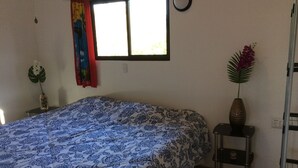 A bedroom with a bed, a window, a nightstand, and a plant. - Fancy holidays in paradise? Make yourself at home! (Parrita)