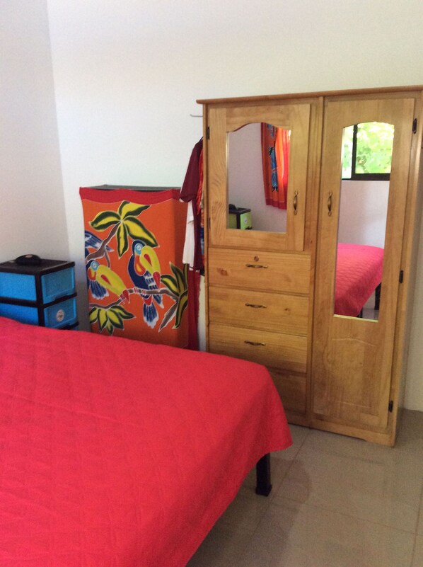 A bedroom with a bed, a wardrobe with a mirror, and a colorful cabinet.