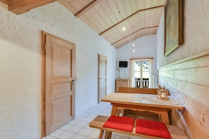 Un intérieur en bois comprenant une table à manger, des bancs, un téléviseur et une porte.