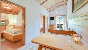 Una habitación con una cama de madera, una mesa con una vela y un televisor en la pared.