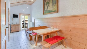 Un interior de madera con una mesa de comedor, bancos, un televisor y un cuadro en la pared.