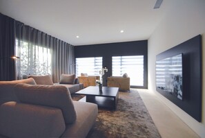 Relax in this stylish living room with a large sofa, coffee table, and armchairs.
