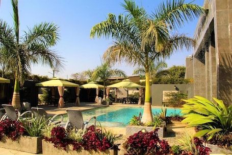 Una piscina al aire libre, sombrillas, sillones reclinables de piscina. Urban Bliss Hotel