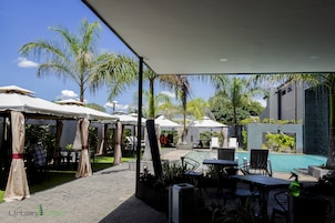 Un patio al aire libre con sombrillas, asientos y una piscina.