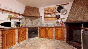 Una cocina con armarios de madera, microondas, estufa y pared de piedra.