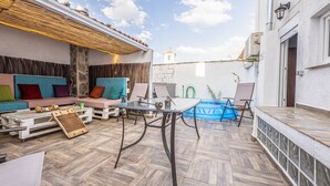 Un patio exterior con una mesa de vidrio, una piscina inflable azul y un edificio blanco al fondo.