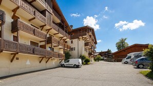 Un edificio de varios pisos con balcones, un estacionamiento y un cielo despejado.