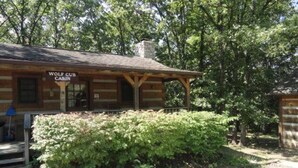 A rustic cabin labeled 'Wolf Cub Cabin' with a wooden exterior, a porch, and a well-maintained garden in front.