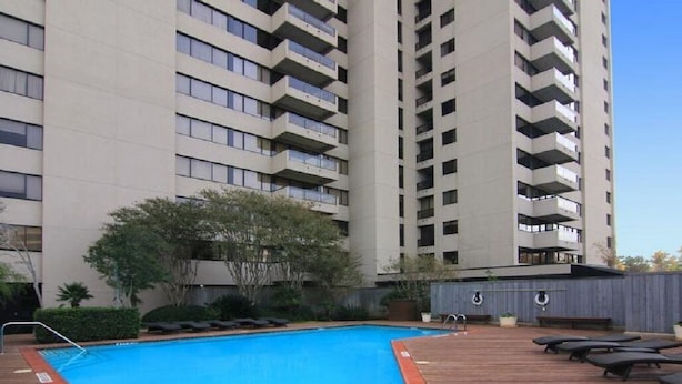 En moderne skyskraber med swimmingpool og lounge på taget.