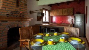 A dining area with a brick fireplace, wooden chairs, a green tablecloth, and yellow plates. - Perfect for honeymoon C10 (Lázaro Cárdenas)